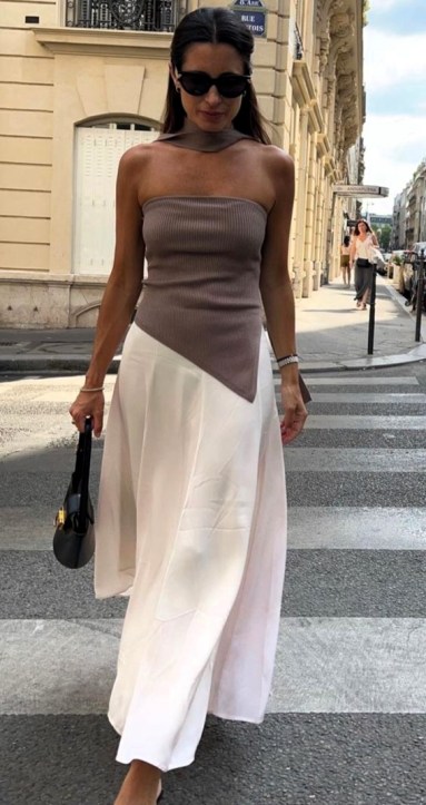 Mulher caminhando na rua usando um top ajustado marrom e uma saia longa branca.